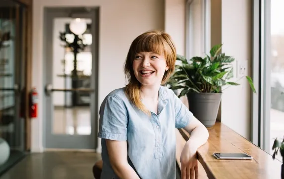 Woman smiling beside a sunny window