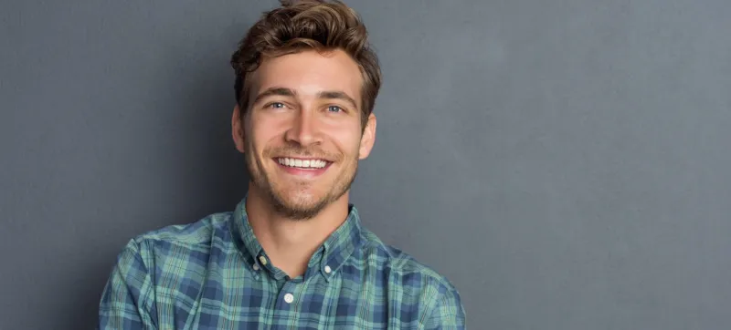 Man with a confident smile against a grey wall